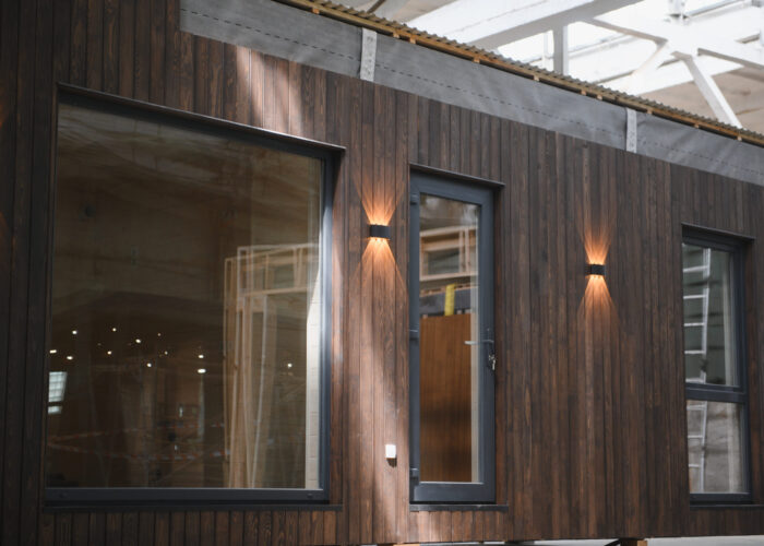Workshop for the production of wooden modular houses dark wooden solid wall panels with windows installed